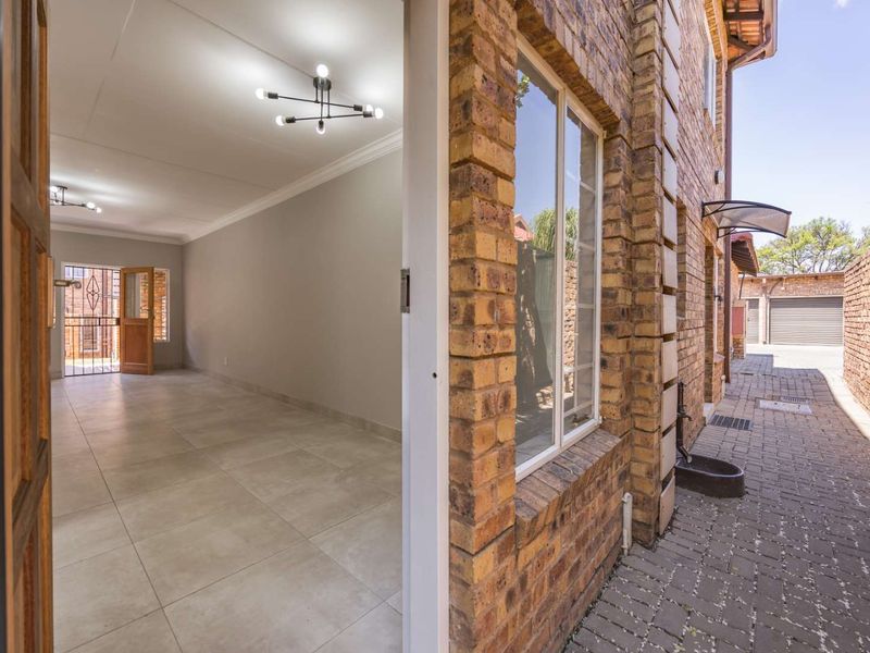 View from the exterior entrance looking into a bright, open-plan living space with neutral tiled floors and modern lighting.