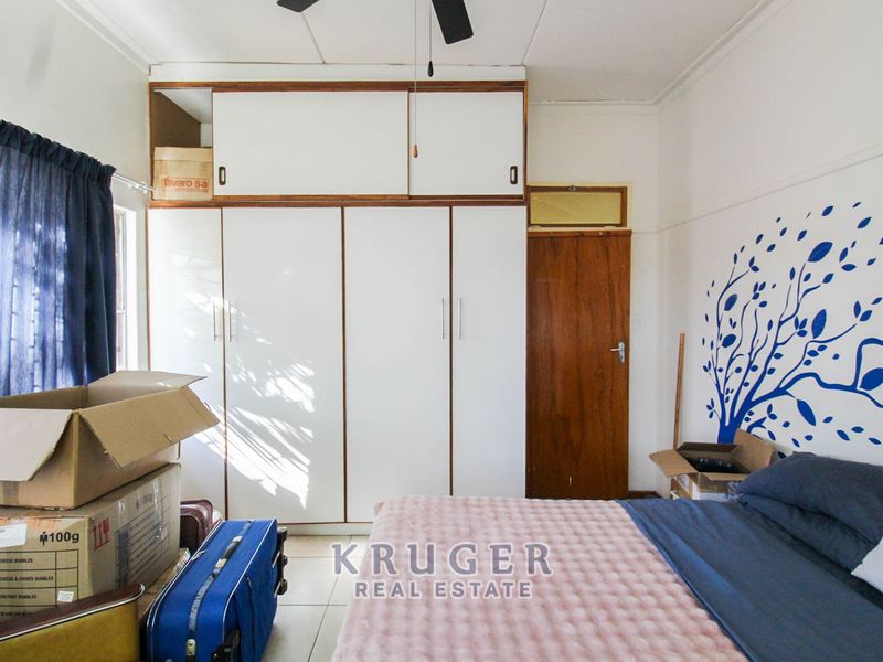 A bedroom featuring built-in cupboards with overhead storage, a ceiling fan, and tiled flooring.