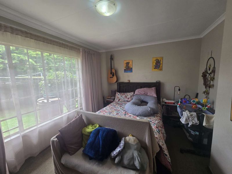 A bedroom featuring a large window providing natural light and a standard ceiling light fixture.