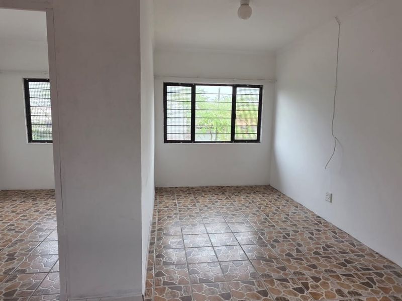 An empty bedroom featuring tiled flooring and security bars on the windows, providing a blank canvas for potential renovation or staging.