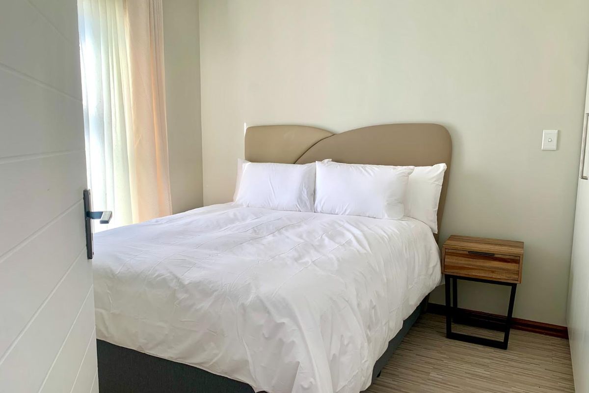 A well-maintained bedroom featuring light-toned laminate flooring, neutral wall finishes, and a built-in cupboard.