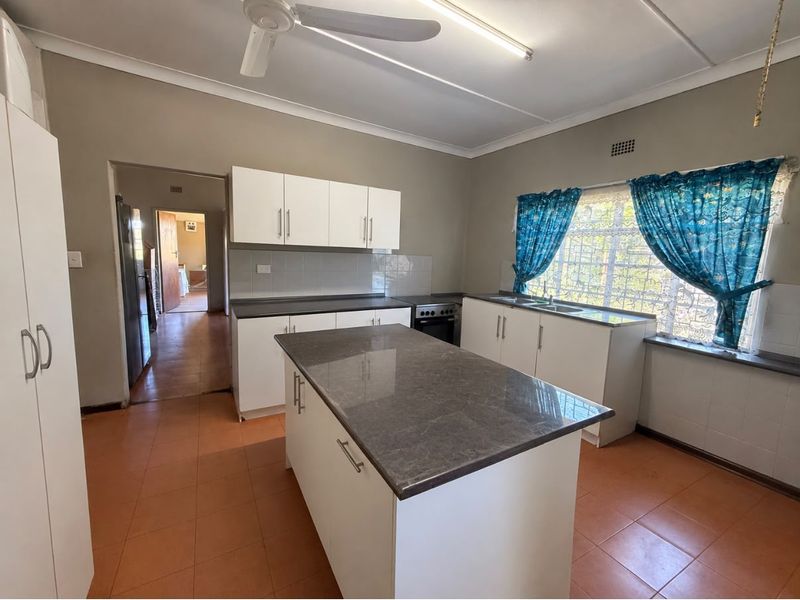 Functional kitchen featuring a central island, stone countertops, built-in cabinetry, and tiled flooring, offering a practical layout for daily meal preparation.