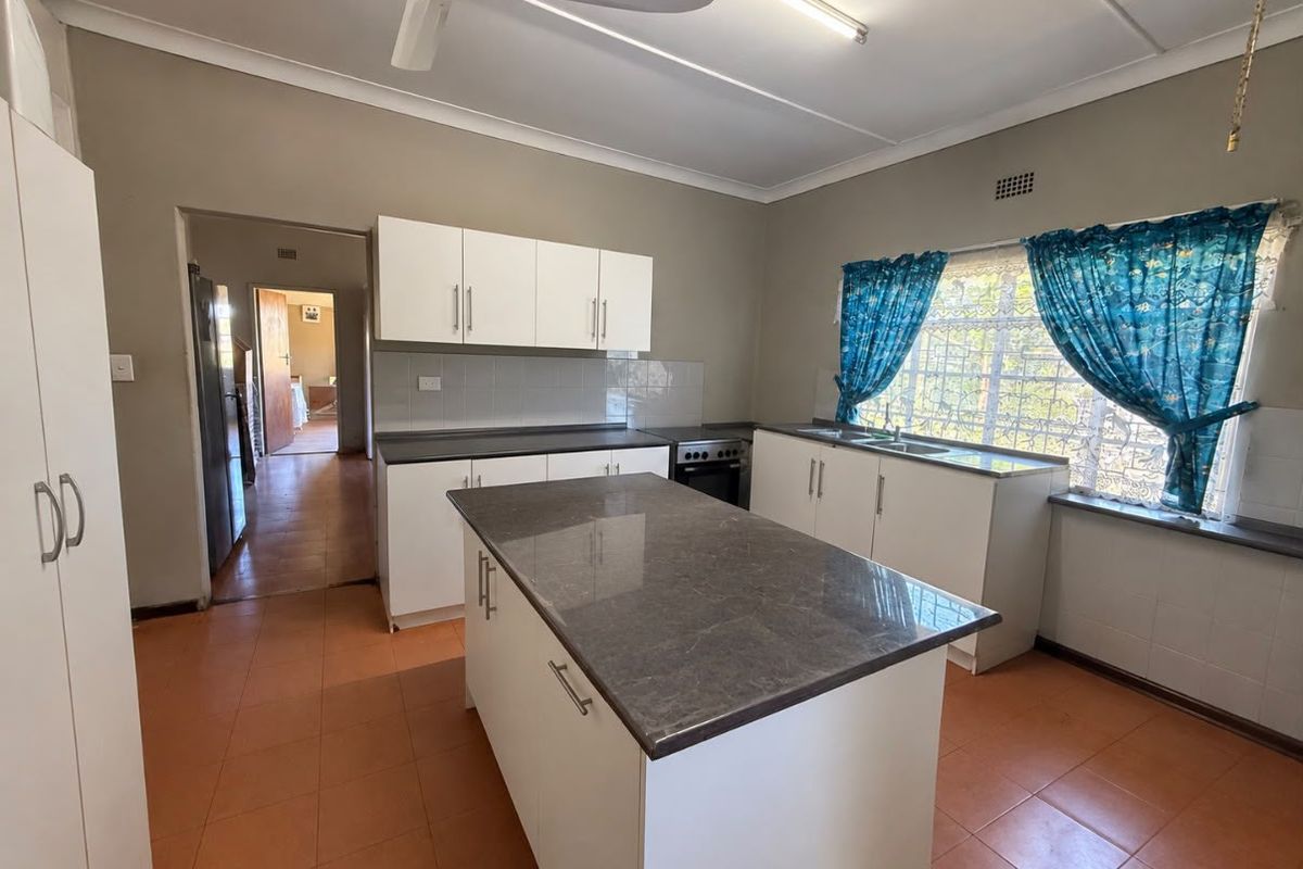 Functional kitchen featuring a central island, stone countertops, built-in cabinetry, and tiled flooring, offering a practical layout for daily meal preparation.