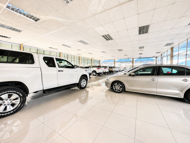 Spacious retail showroom featuring high-gloss tiled flooring, extensive glass curtain walls for natural light, and a suspended ceiling with integrated lighting.