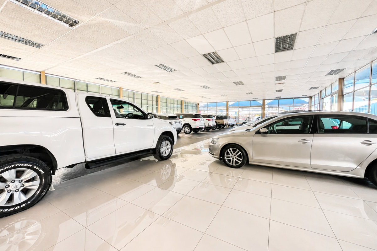 Spacious retail showroom featuring high-gloss tiled flooring, extensive glass curtain walls for natural light, and a suspended ceiling with integrated lighting.