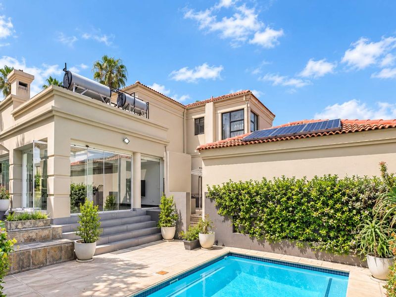 Rear exterior view featuring a swimming pool, tiled patio area, solar water heating system, and photovoltaic panels on the roof.