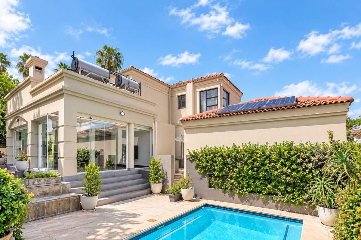 Rear exterior view featuring a swimming pool, tiled patio area, solar water heating system, and photovoltaic panels on the roof.