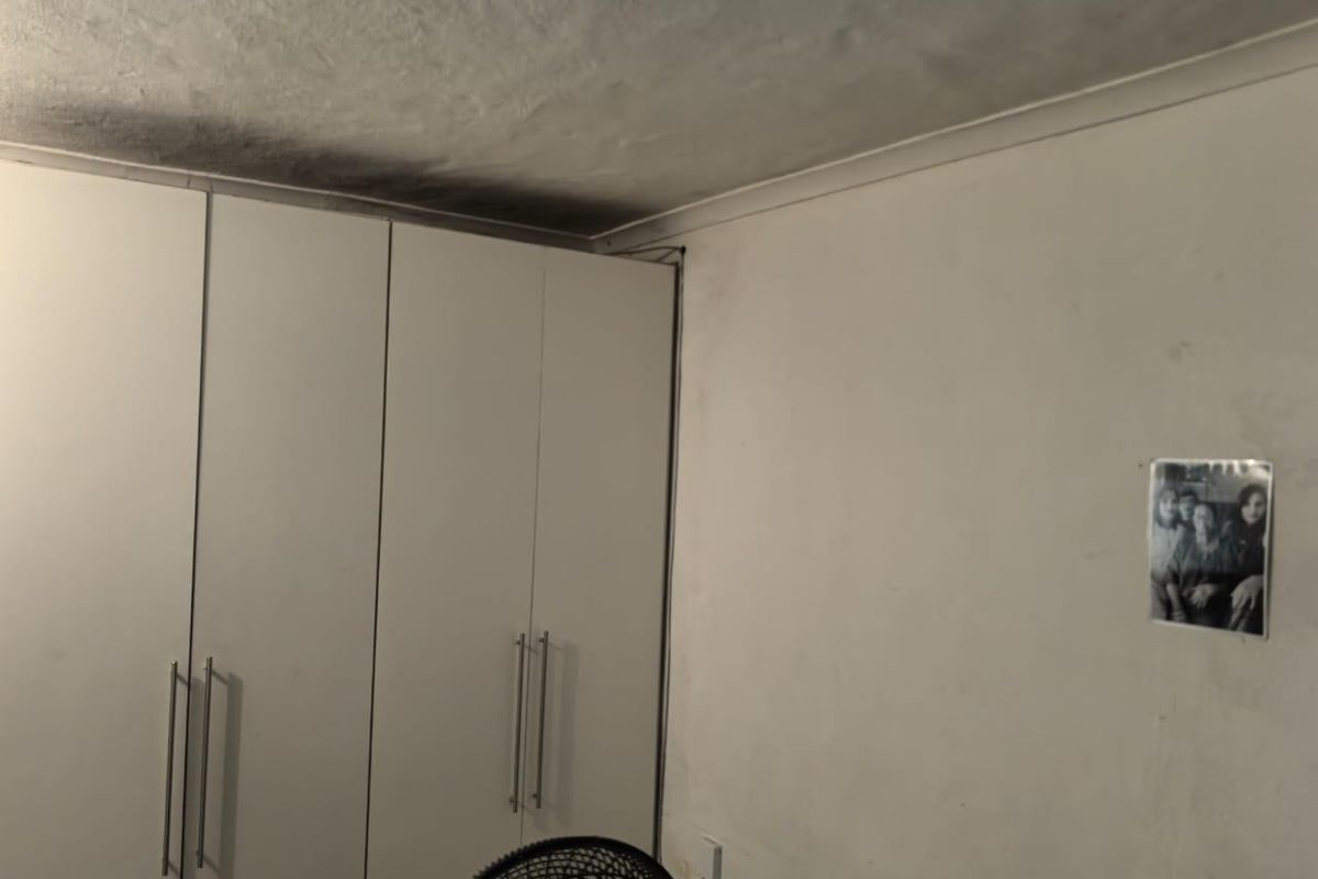 Bedroom featuring built-in wardrobes with visible ceiling staining and wall surface wear requiring maintenance and cosmetic attention.