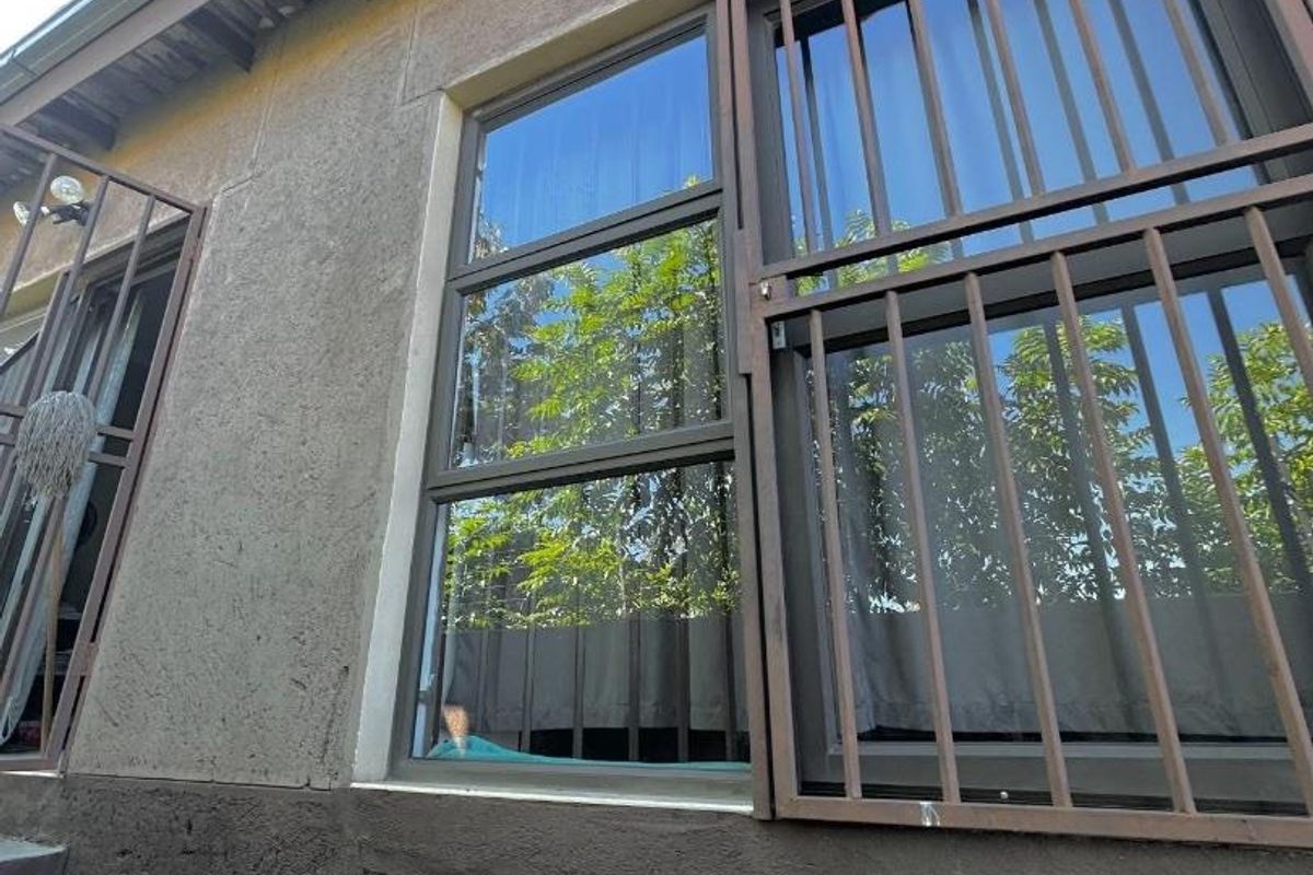 Exterior view of the townhouse facade featuring security bars on windows and mounted exterior lighting fixtures.