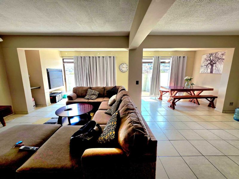 Spacious open-plan living and dining area featuring tiled flooring and large sliding glass doors that provide ample natural light.