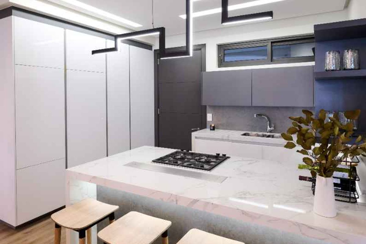 Modern kitchen featuring a central island with a built-in gas hob, sleek cabinetry, and contemporary pendant lighting.