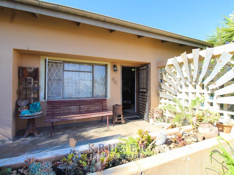 A covered patio area featuring a concrete planter, security gate, and security bars on the window, offering a functional outdoor space.
