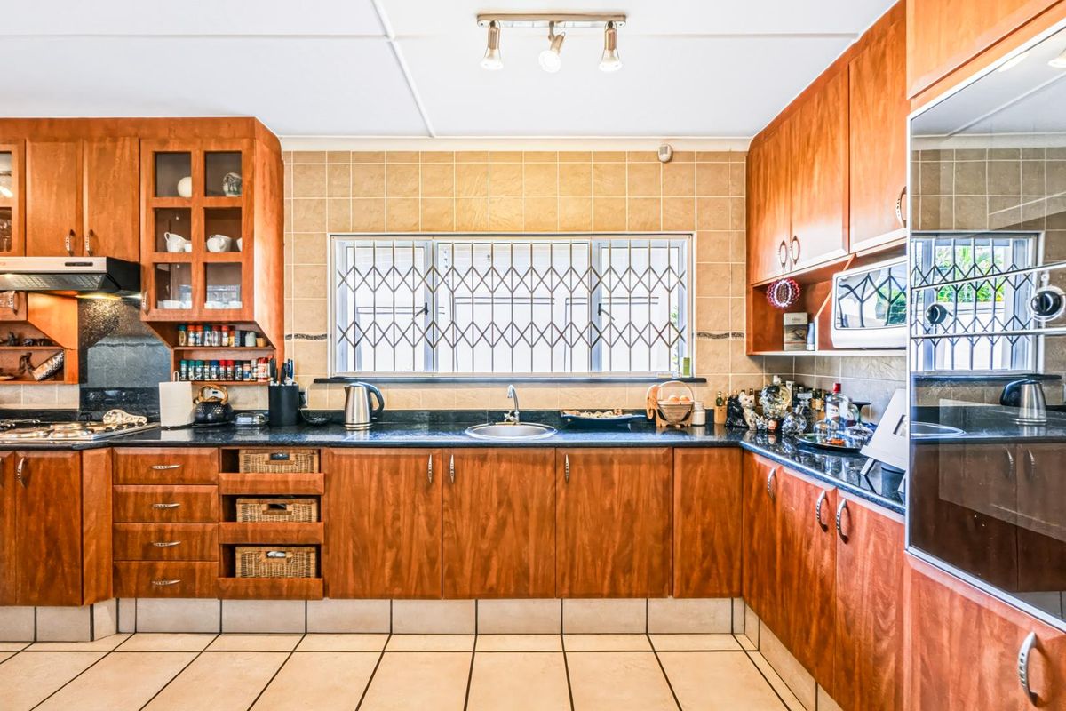 A functional kitchen featuring warm-toned wooden cabinetry, granite countertops, a tiled backsplash, and integrated appliances, providing a classic and practical cooking space.