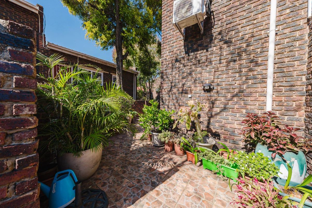 A private rear courtyard featuring a brick facade, tiled flooring, and an external air conditioning unit.
