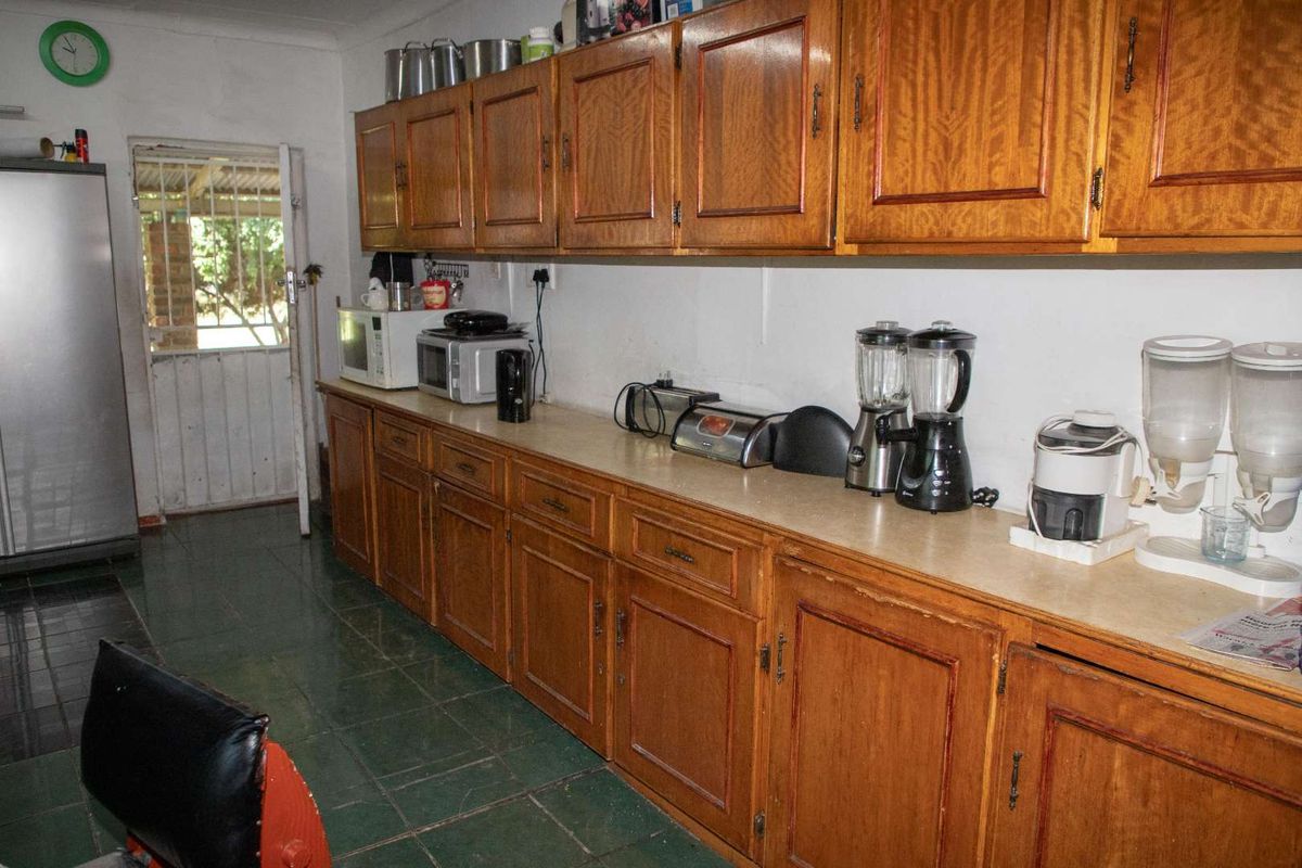 A functional kitchen featuring extensive wooden cabinetry, laminate countertops, and tiled flooring, providing ample storage space with direct access to the exterior.