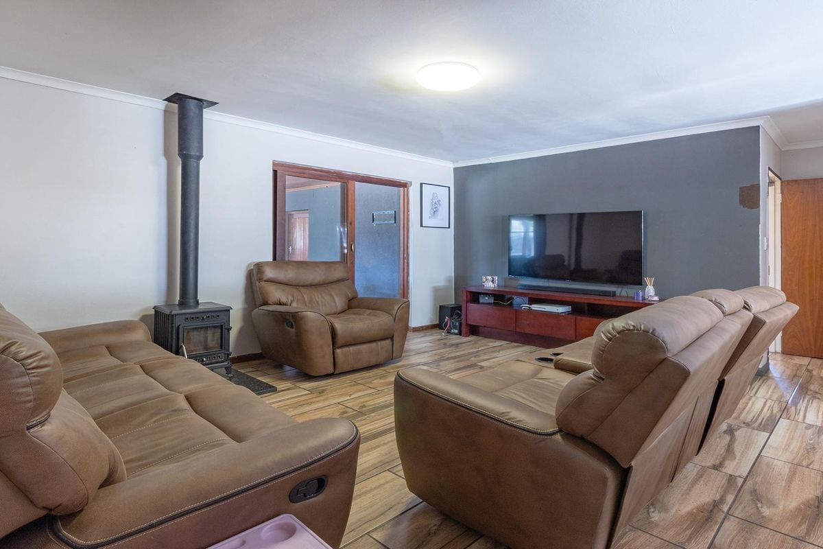 Spacious living room featuring a wood-burning fireplace, wood-look tiled flooring, and a feature wall, providing a comfortable and functional family living space.