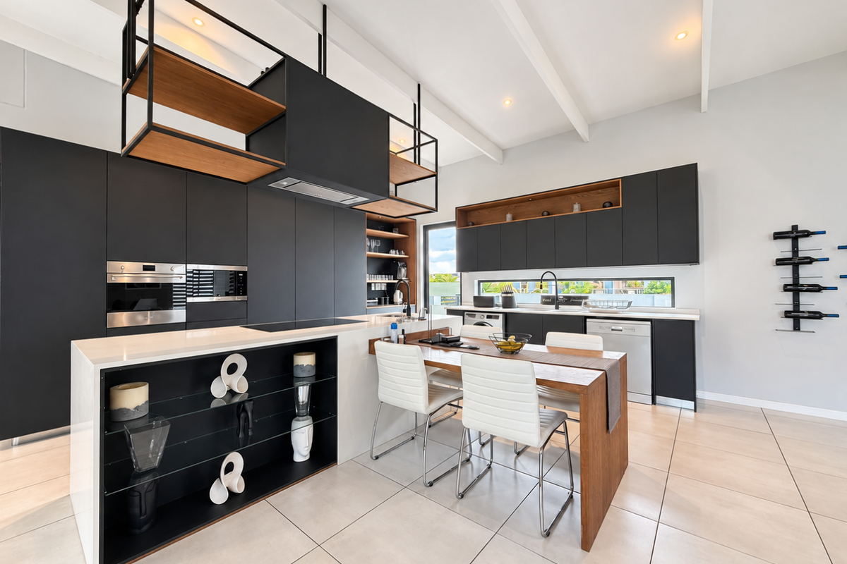 Modern, high-end kitchen featuring sleek matte black cabinetry, a central island with integrated dining, premium built-in appliances, and stylish exposed ceiling beams.