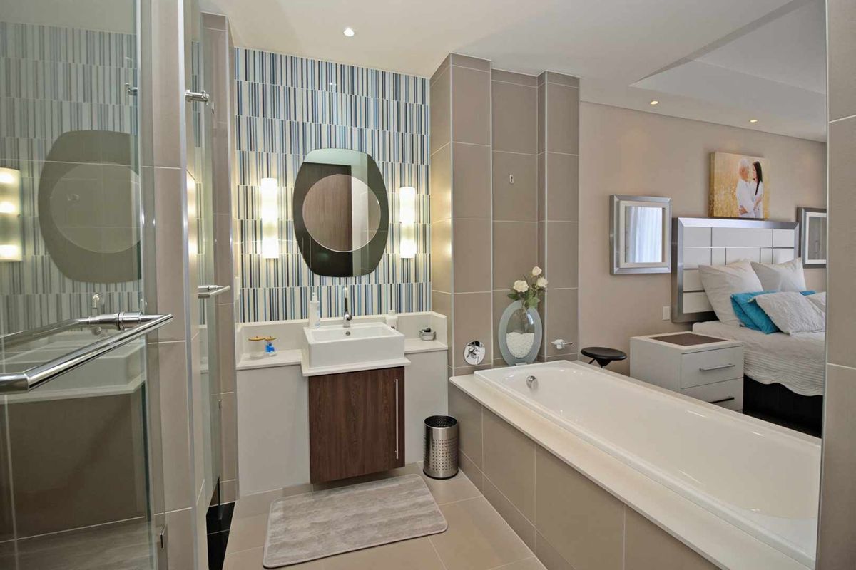 Modern en-suite bathroom featuring a floating vanity, built-in bathtub, and glass-enclosed shower, seamlessly integrated with the adjacent bedroom area.