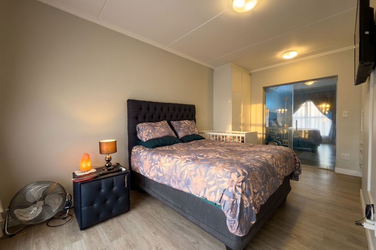 A well-maintained bedroom featuring light wood-look flooring, built-in cabinetry, and a glass-partitioned entrance leading to an adjacent space.