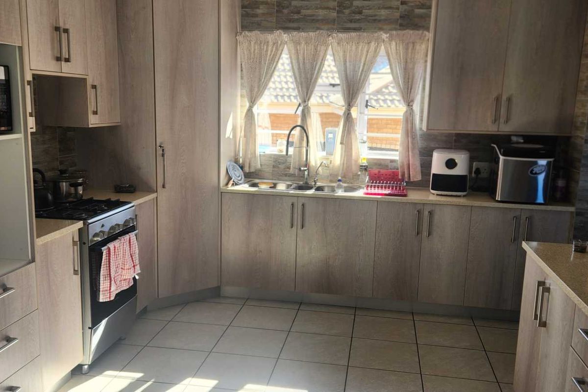A functional kitchen featuring light wood-grain cabinetry, stone-look countertops, tiled flooring, and a built-in gas stove with an integrated oven.
