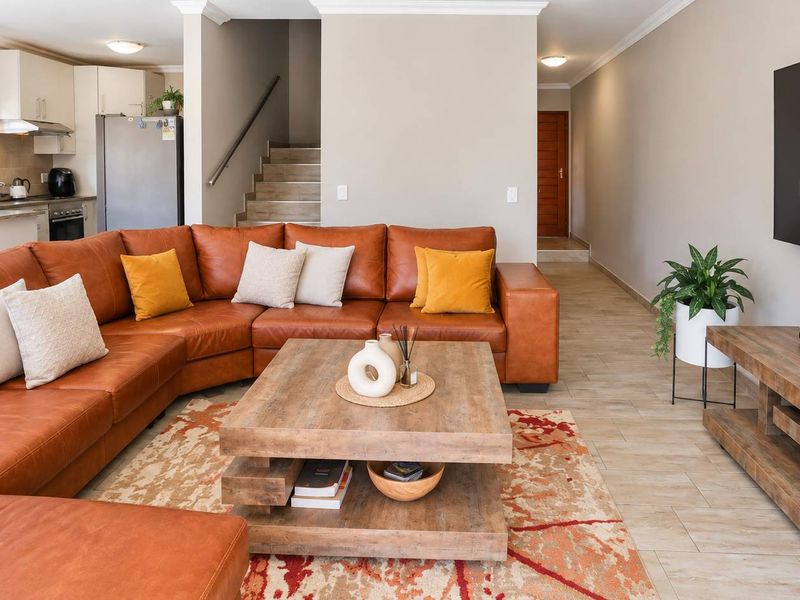 Open-plan living area featuring tiled flooring, a modern kitchen with built-in cabinetry, and a staircase leading to the upper level.