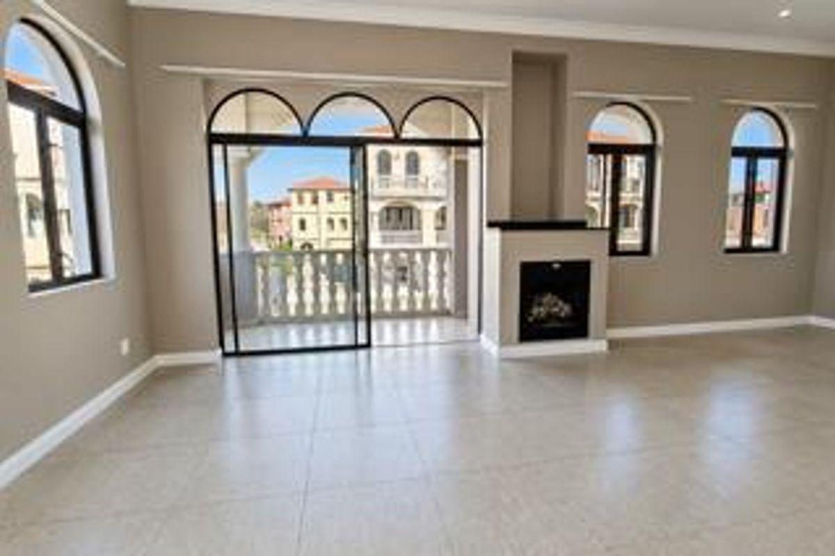 Spacious living area featuring tiled floors, a built-in fireplace, and large arched windows with direct access to a private balcony.