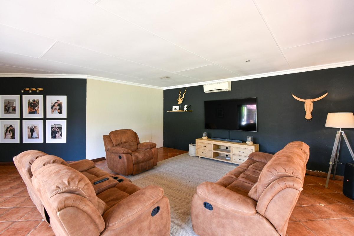 A comfortable living room featuring dark accent walls, tiled flooring, and a wall-mounted air conditioning unit.