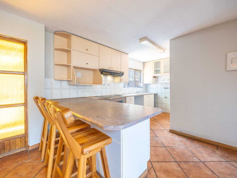 Functional kitchen featuring built-in cabinetry, a breakfast bar, tiled backsplash, and ceramic tile flooring, offering a practical layout for daily meal preparation.