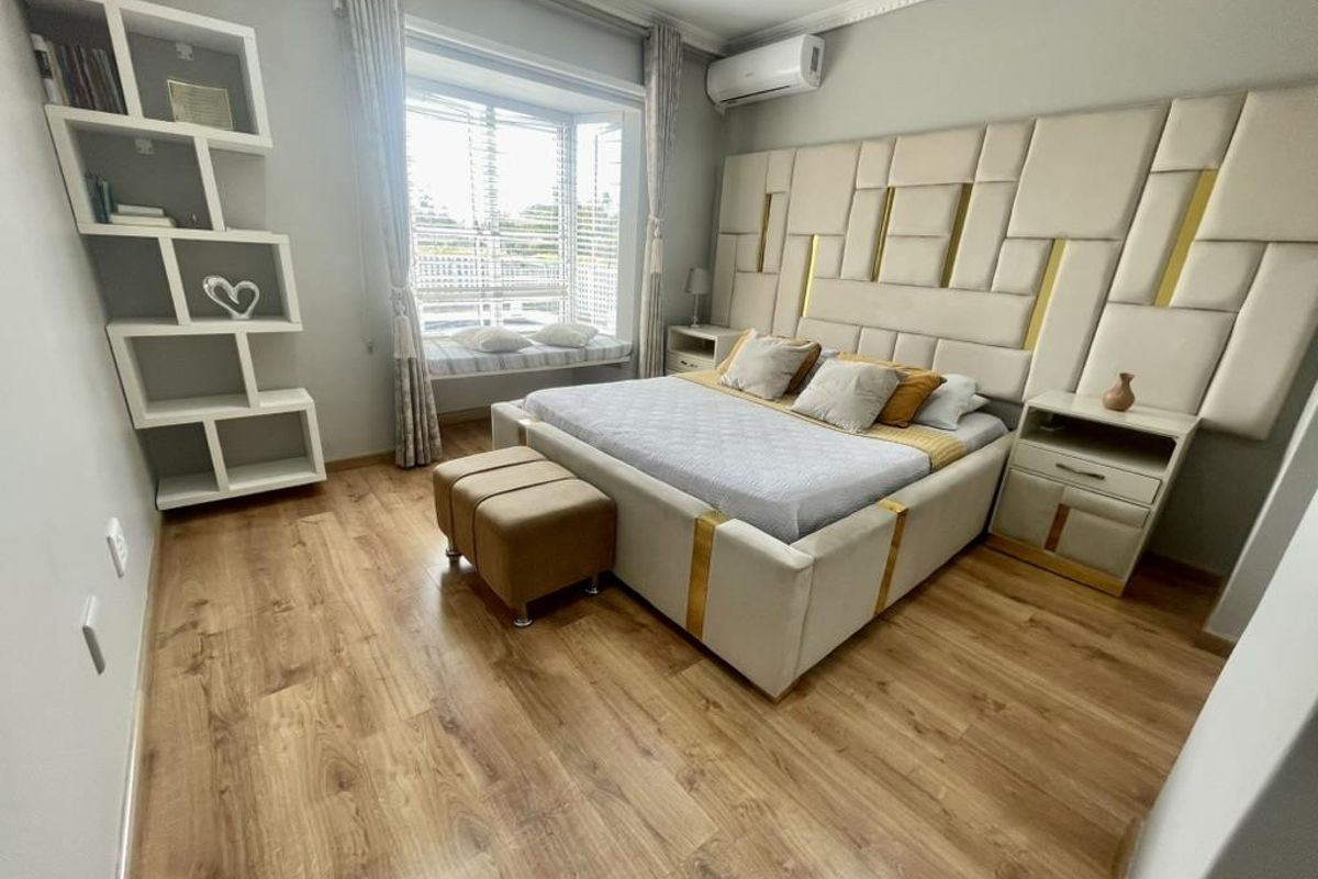 A well-maintained bedroom featuring laminate flooring, a built-in window seat, recessed lighting, and a wall-mounted split-system air conditioner.