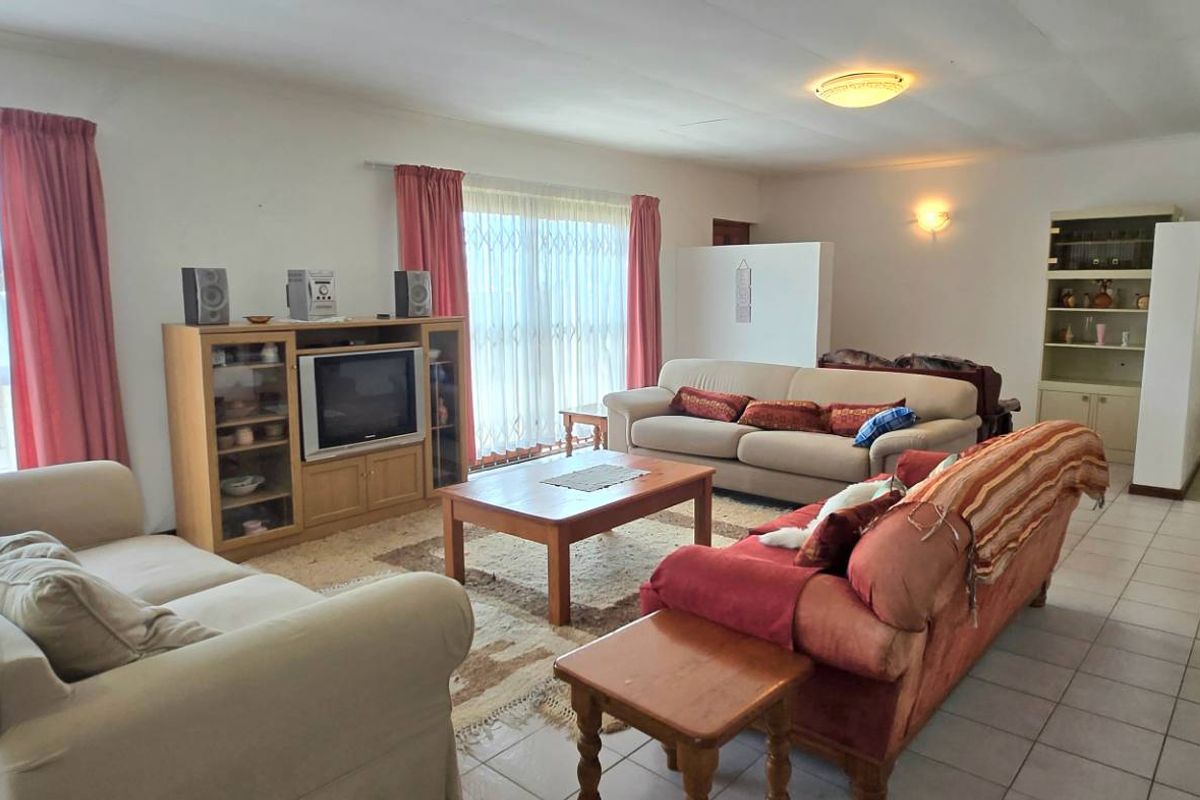 Spacious living room featuring tiled flooring, large windows with natural light, and an open-plan layout leading to a hallway.