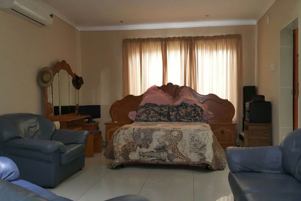 Spacious bedroom featuring tiled flooring, neutral wall finishes, and a wall-mounted air conditioning unit.