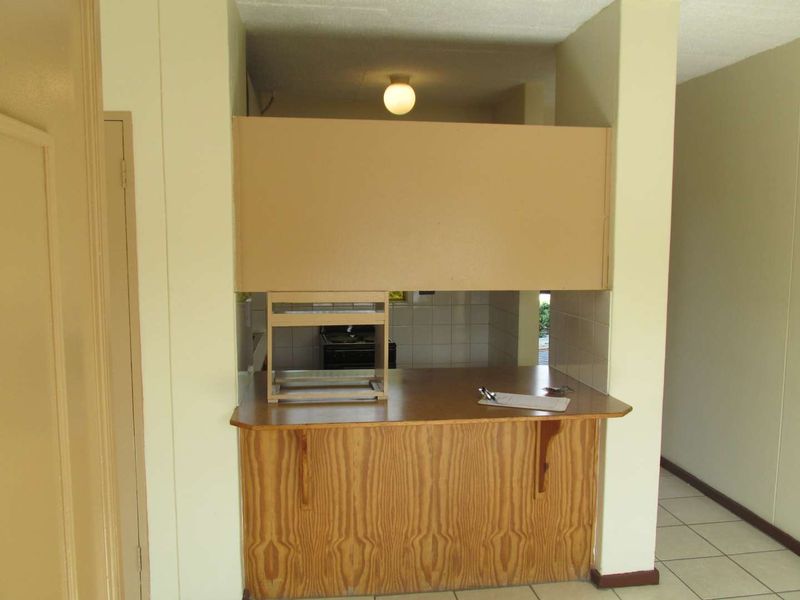 A dated kitchen area featuring a breakfast bar, tiled flooring, and built-in cabinetry, offering a functional layout ready for modernization.