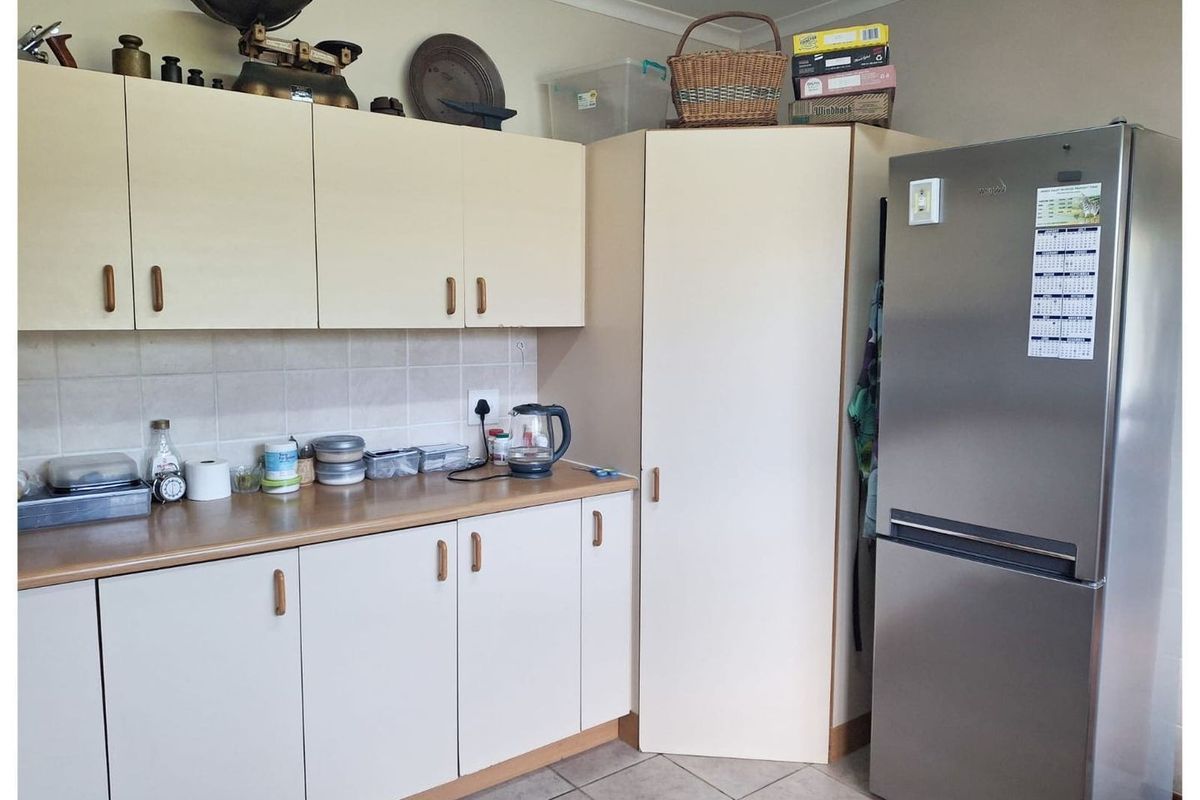 A functional kitchen area featuring laminate cabinetry, tiled splashbacks, and tiled flooring, providing practical storage and workspace.
