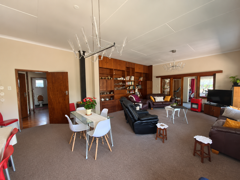 Spacious open-plan living and dining area featuring built-in wooden cabinetry, modern lighting fixtures, and direct access to adjacent rooms.