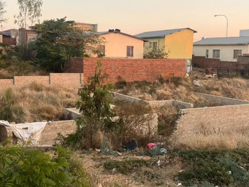 Vacant residential land featuring an unfinished brick foundation and perimeter walling, situated in a developed neighborhood setting.