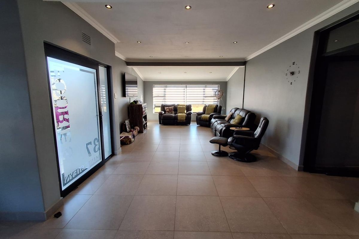 Spacious living room featuring large format floor tiles, recessed downlighting, and a sliding glass door providing natural light.