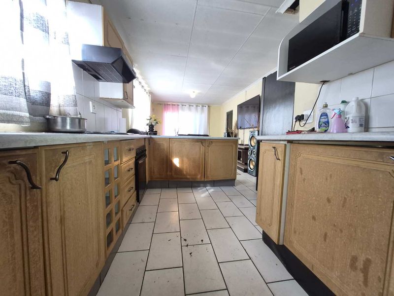 A dated kitchen featuring laminate cabinetry, built-in appliances, and tiled flooring. The space offers a functional layout ready for modern updates and cosmetic renovation.