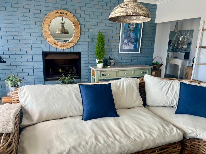 A cozy living room featuring a distinctive blue painted brick feature wall with a built-in fireplace and a rustic pendant light fixture.