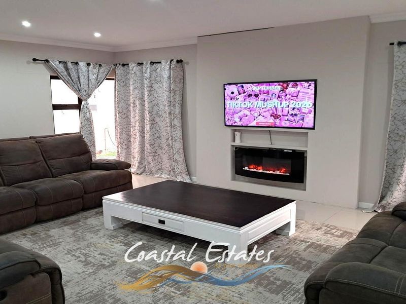 A comfortable living room featuring a built-in fireplace, recessed lighting, and neutral tiled flooring.