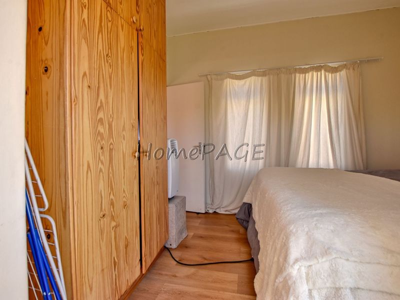 A bedroom featuring laminate flooring and a large built-in wooden wardrobe, offering functional storage space within the retirement village unit.