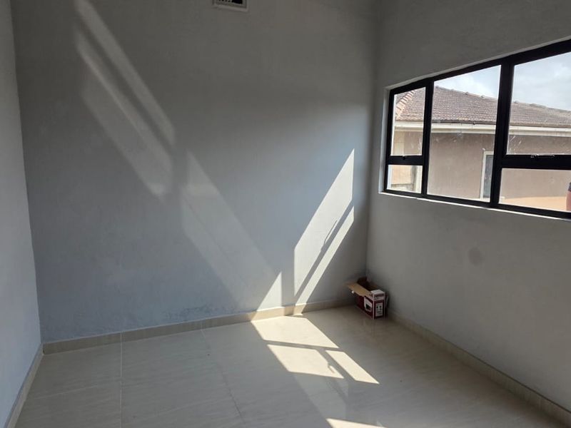 A bright, empty bedroom featuring tiled flooring and aluminium-framed windows, offering a clean, neutral space ready for personalization.