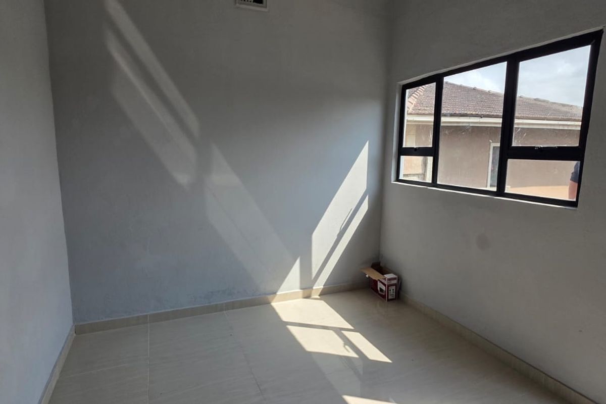 A bright, empty bedroom featuring tiled flooring and aluminium-framed windows, offering a clean, neutral space ready for personalization.