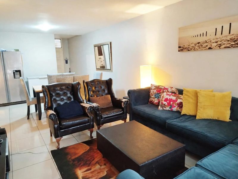 An open-plan living and dining area featuring neutral tiled flooring and recessed lighting, providing a functional space for relaxation and meals.
