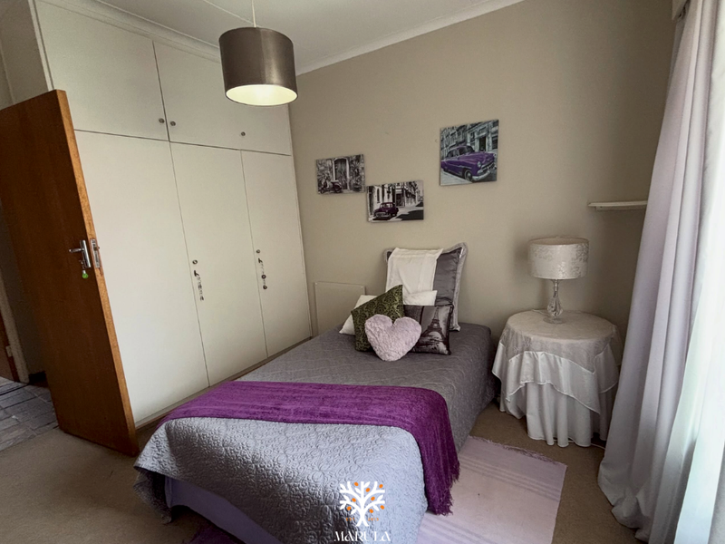 A bedroom featuring built-in cupboards, carpeted flooring, and a pendant light fixture.