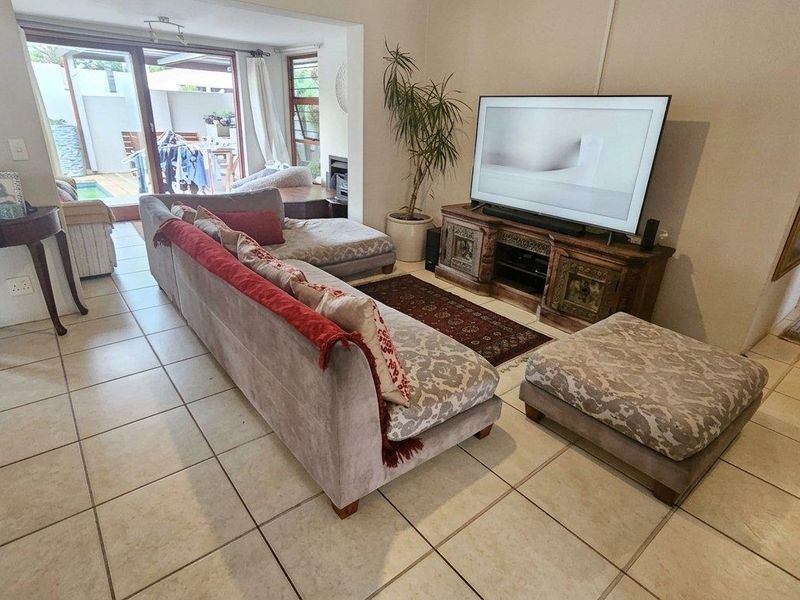 Spacious living room featuring neutral tiled flooring and large sliding glass doors that provide direct access to the outdoor patio and pool area.