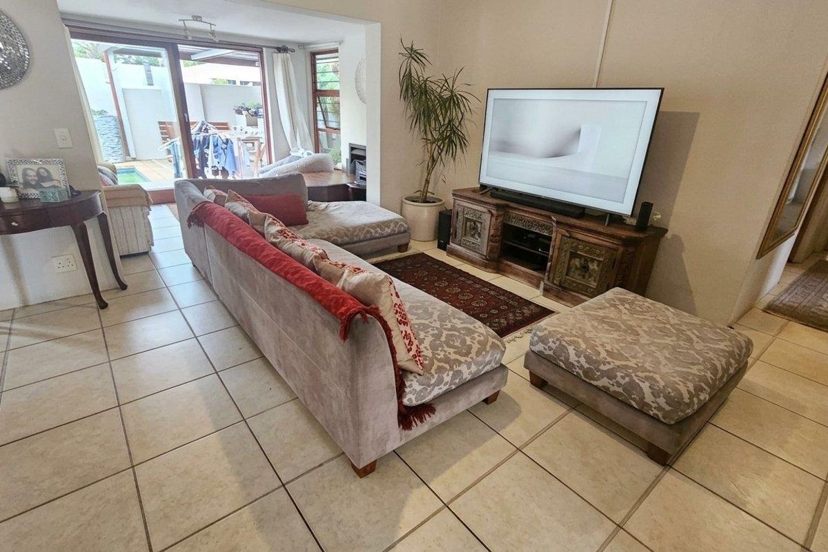 Spacious living room featuring neutral tiled flooring and large sliding glass doors that provide direct access to the outdoor patio and pool area.