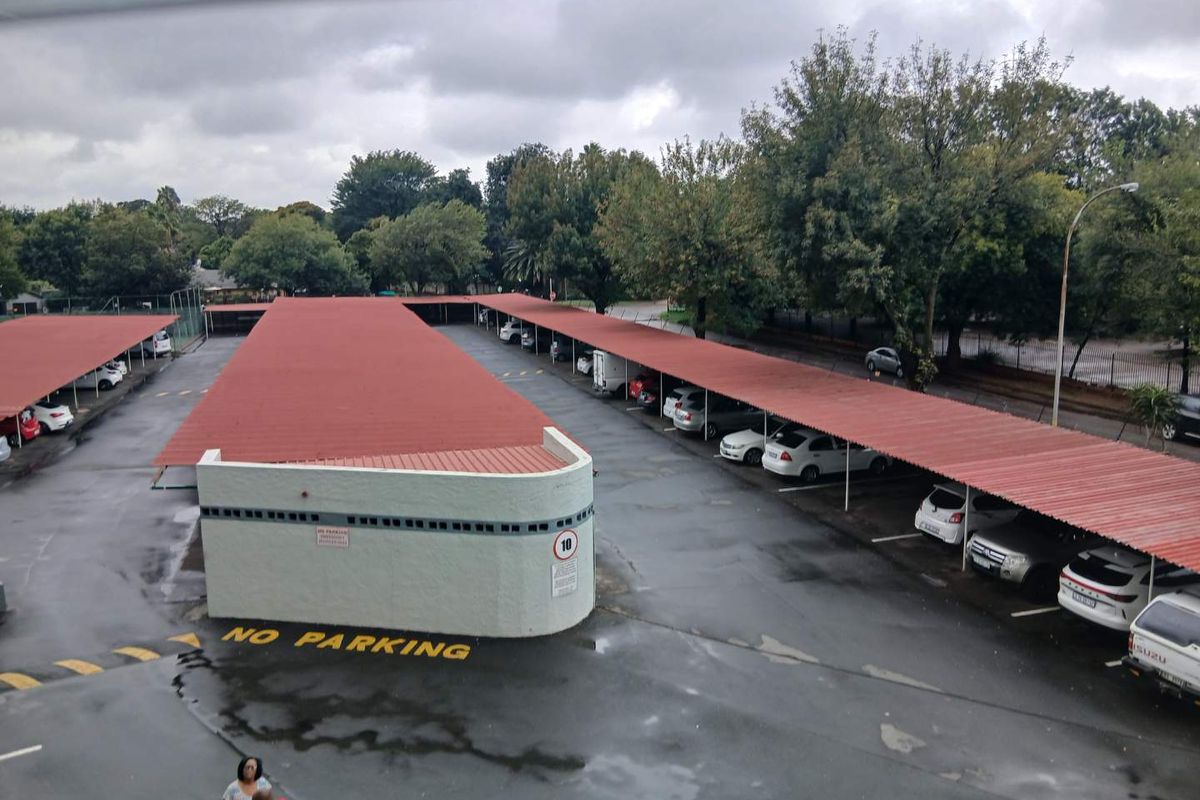 Elevated view of the apartment complex parking area featuring covered carports and paved driveway surfaces.