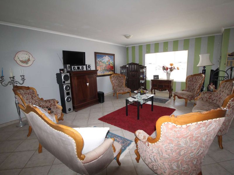 A spacious living room featuring ceramic tiled flooring and a large window, offering a comfortable area for relaxation and family gatherings.