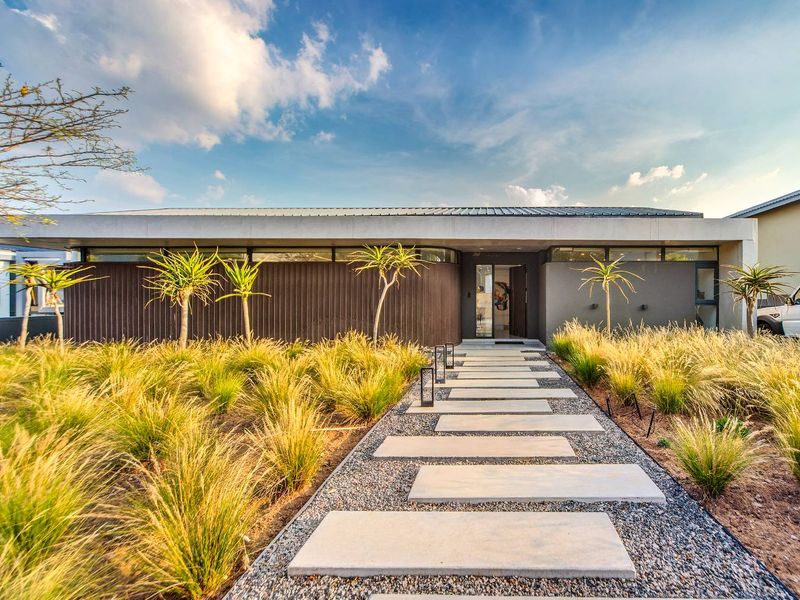 A modern front elevation featuring a concrete paver walkway, minimalist landscaping, and contemporary architectural cladding with clerestory windows.