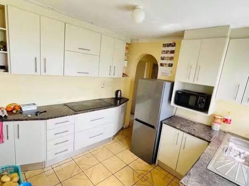 Functional kitchen featuring ample built-in cabinetry, laminate countertops, a stainless steel sink, and ceramic tile flooring.